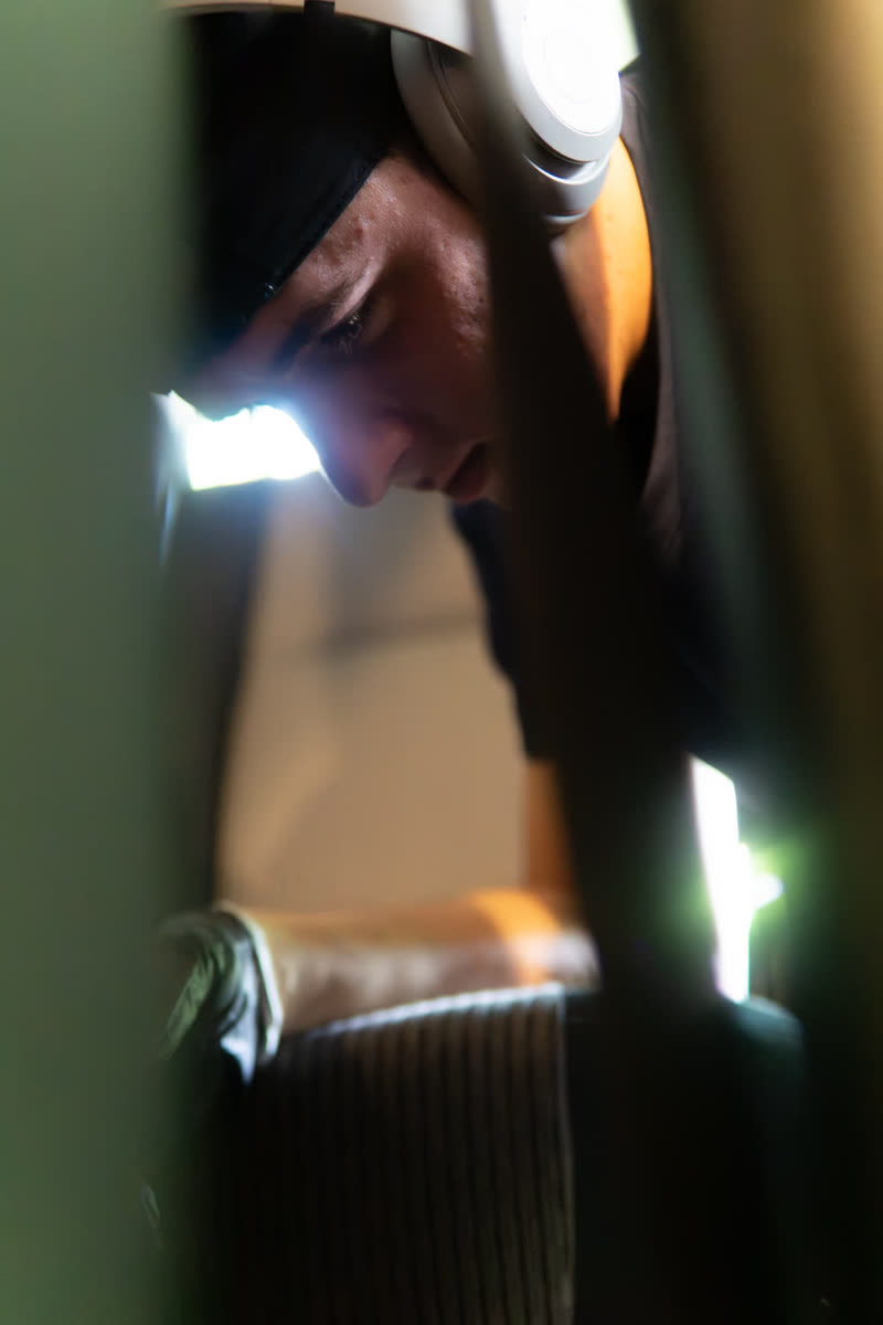 Paden Rhoads leaning into a car, lit by a headlight, working