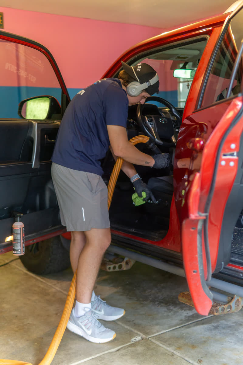 Paden Rhoads vacuuming the front seat of a red Jeep Wrangler